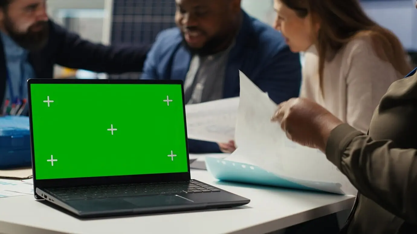 Betriebsleiter einer Industrieanlage tippt auf einem Laptop mit grünem Bildschirm.