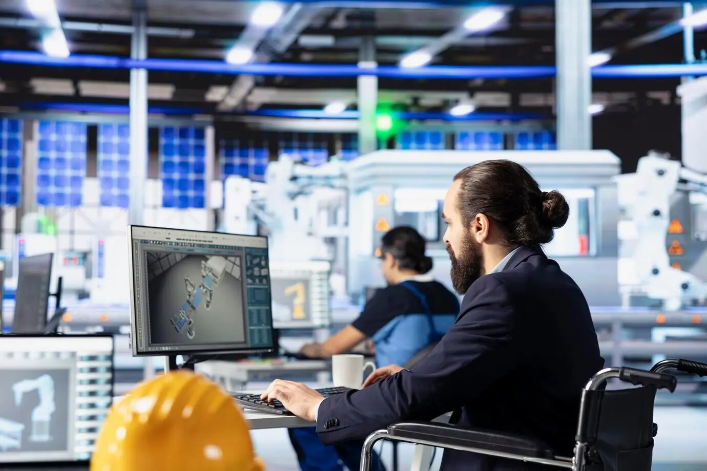 Eine Person mit Behinderung arbeitet am PC in einer Photovoltaikfabrik.